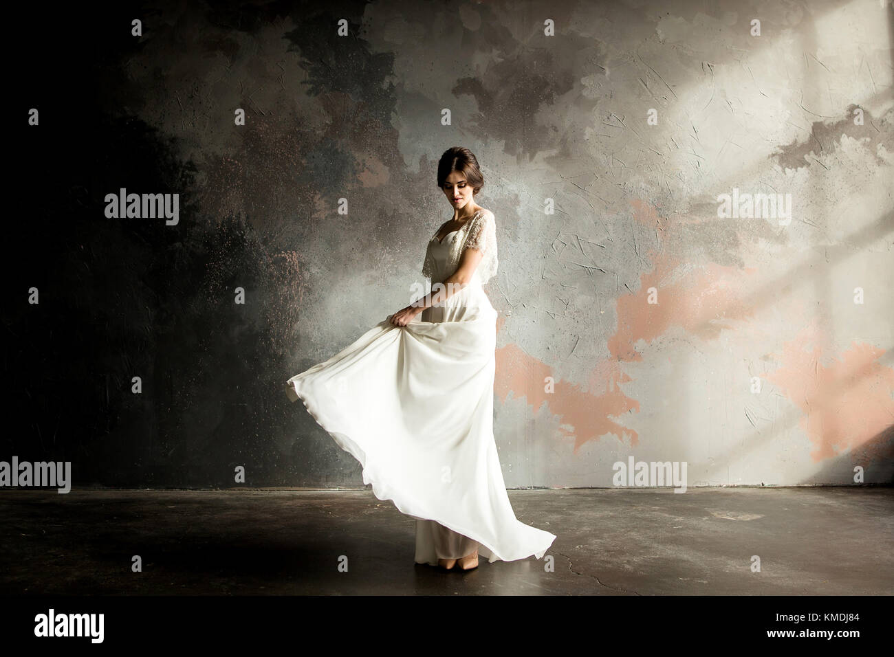 Belle robe de mariée assis sur une chaise à l'intérieur dans dark studio intérieur comme à la maison. Banque D'Images