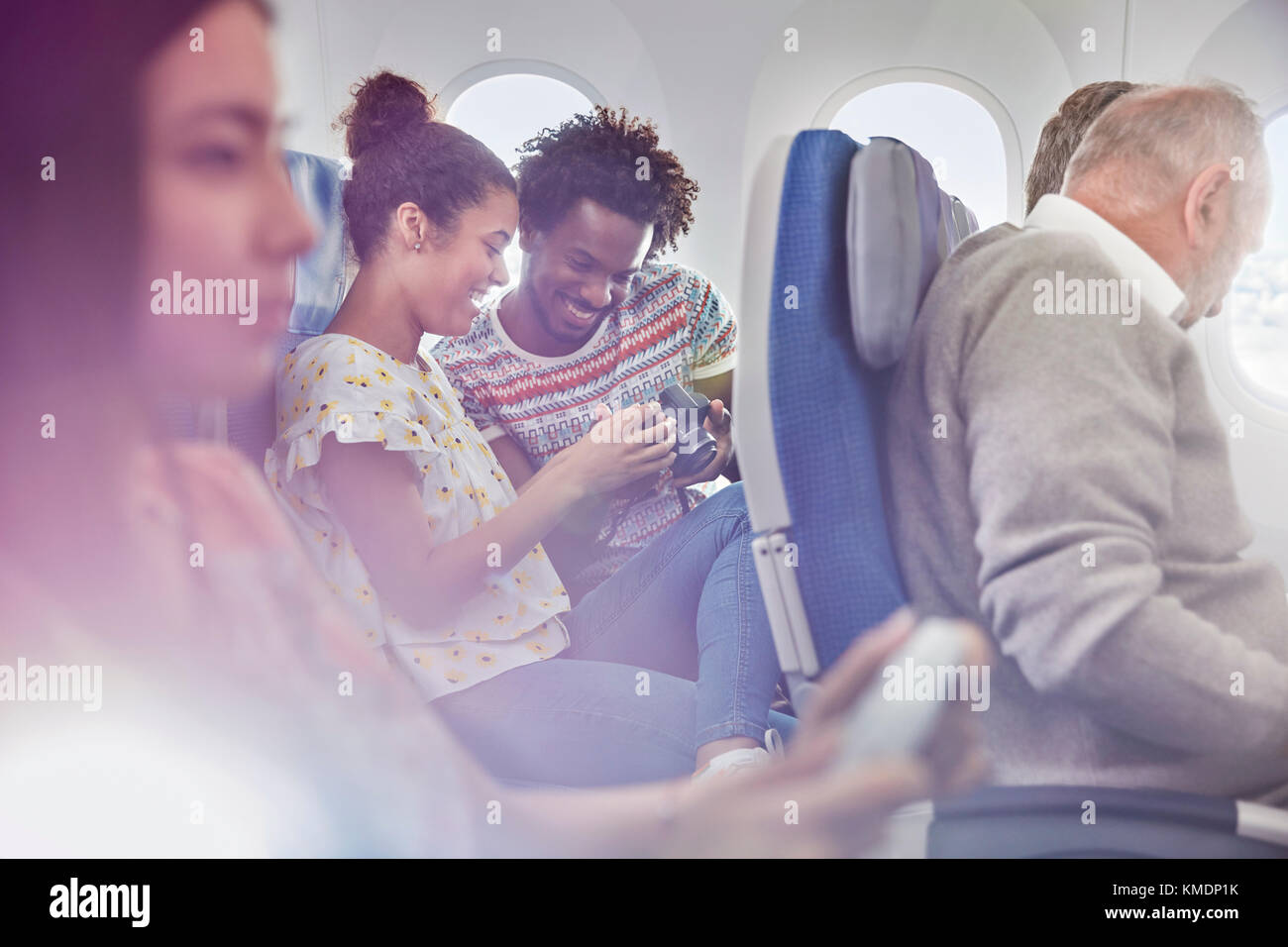 Jeune couple regardant des photos sur un appareil photo numérique en avion Banque D'Images