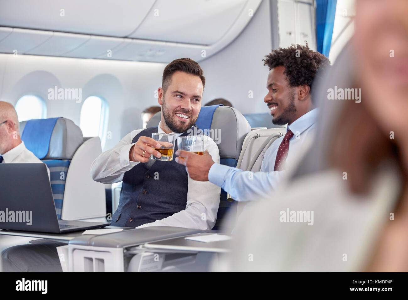 Les hommes d'affaires toasting whiskey lunettes de première classe dans un avion Banque D'Images