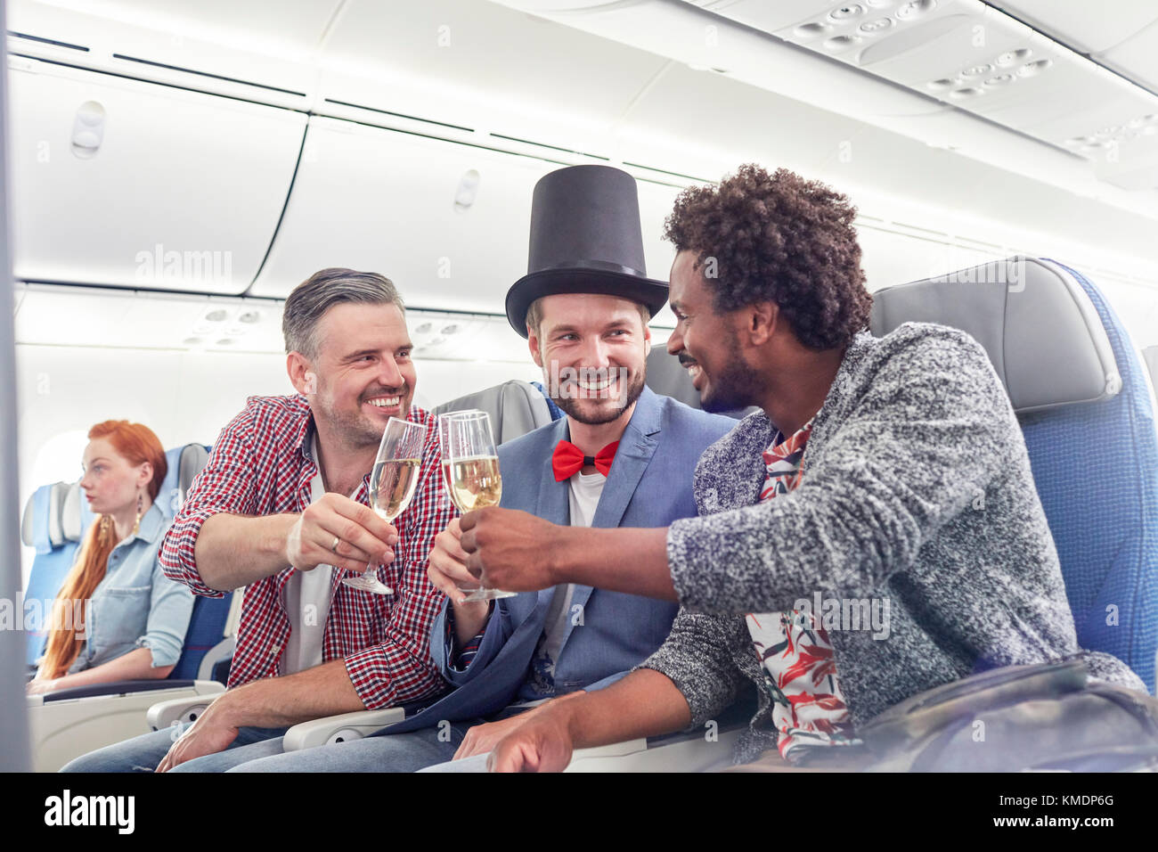 Jeunes amis de sexe masculin qui toastent des verres à champagne en première classe avion Banque D'Images