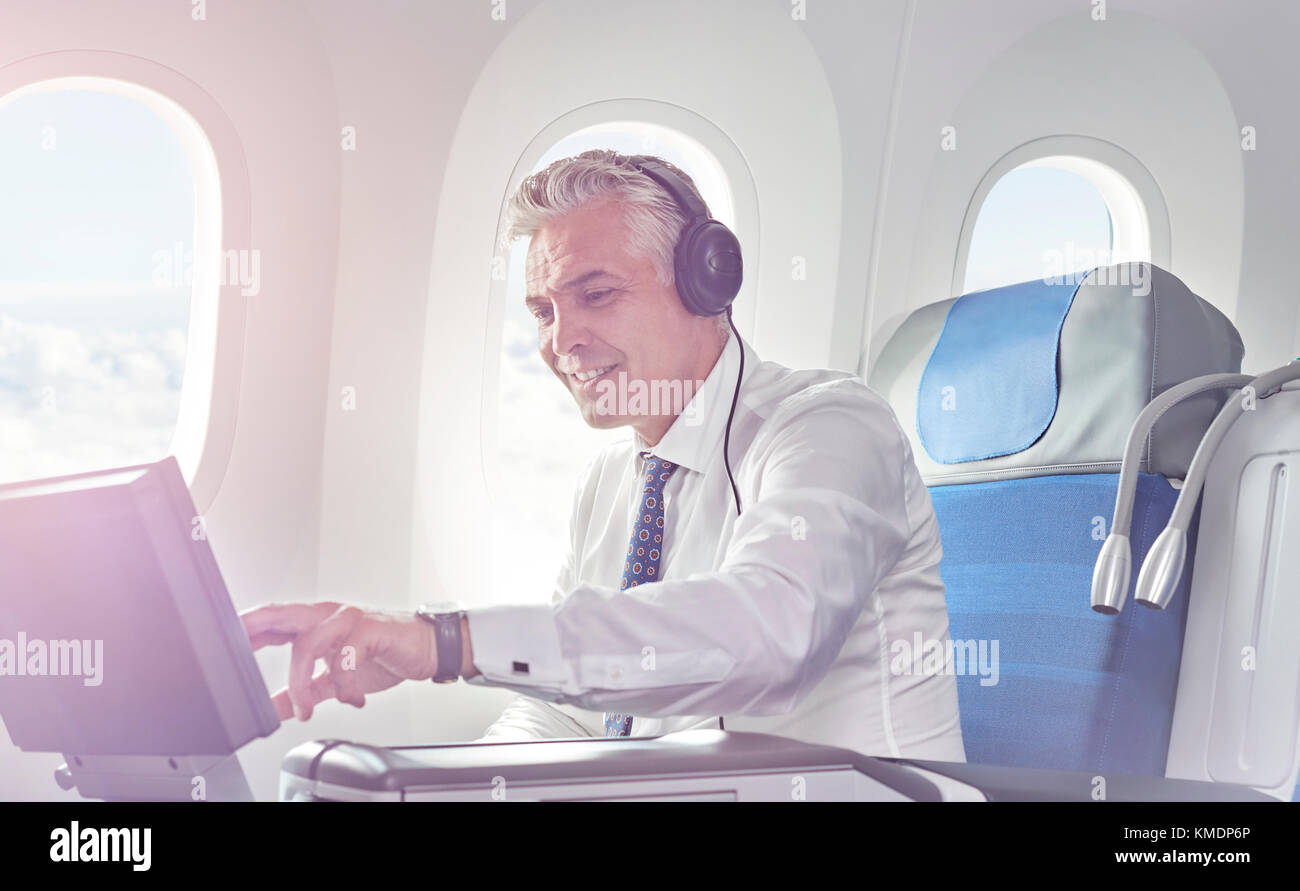 Homme d'affaires avec un casque pour regarder un film dans un avion Banque D'Images