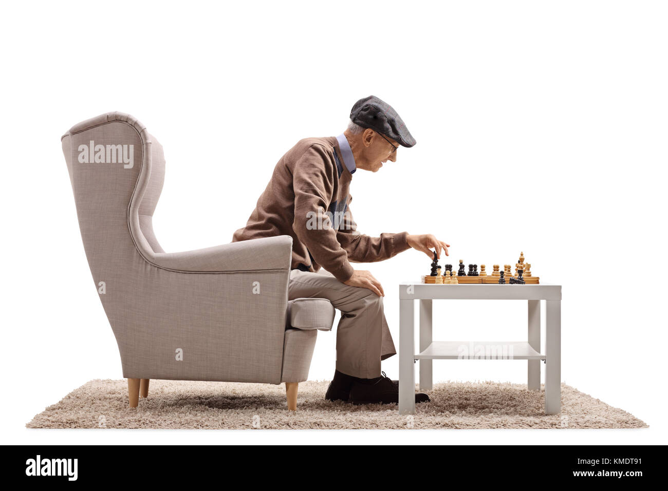 Un homme âgé assis dans un fauteuil et jouer aux échecs avec lui-même isolé sur fond blanc Banque D'Images