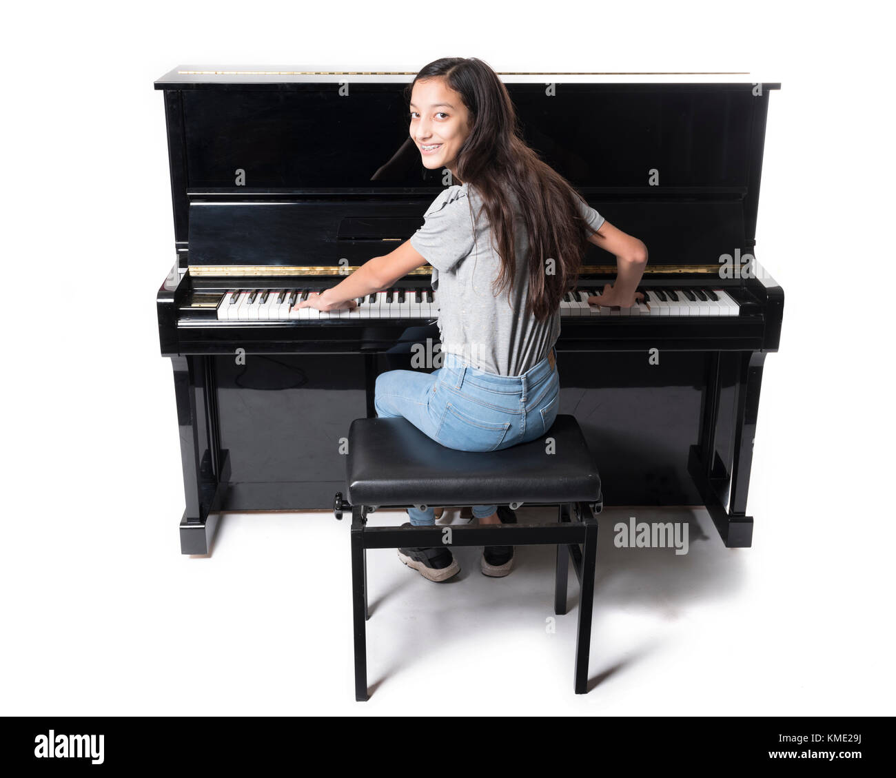 Teenage fille brune et noir piano droit en studio Banque D'Images