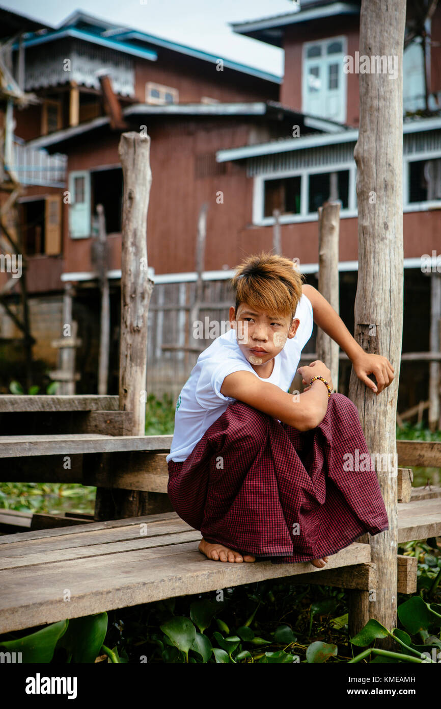 Un garçon se croquant sur la jetée, le lac Inle, Myanmar Banque D'Images