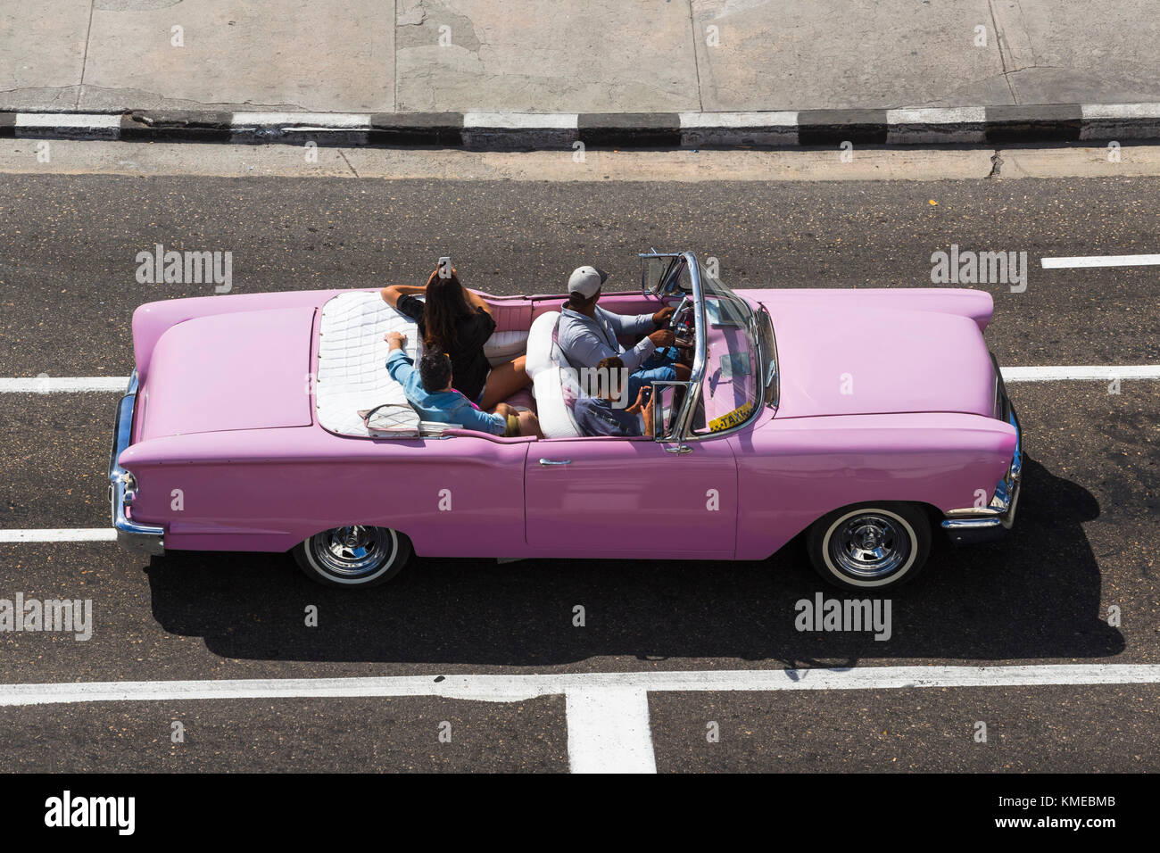 Voiture américaine classique décapotable rose avec chauffeur et touristes cubains, la Havane, Cuba Banque D'Images