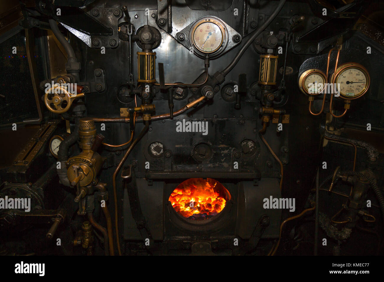 Photo de nuit à l'intérieur de la cabine de locomotive à vapeur, à l'incendie allumé dans la chambre de la plaque arrière de la chaudière. Les soupapes, les tiges, les tuyaux, les manomètres toutes visibles Banque D'Images