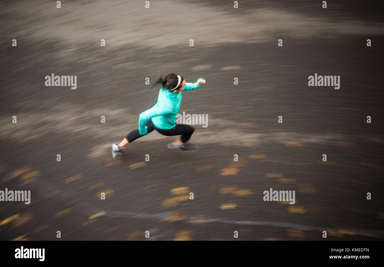 Une image floue d'une jeune femme qui court sur une route filmée par le dessus. Banque D'Images