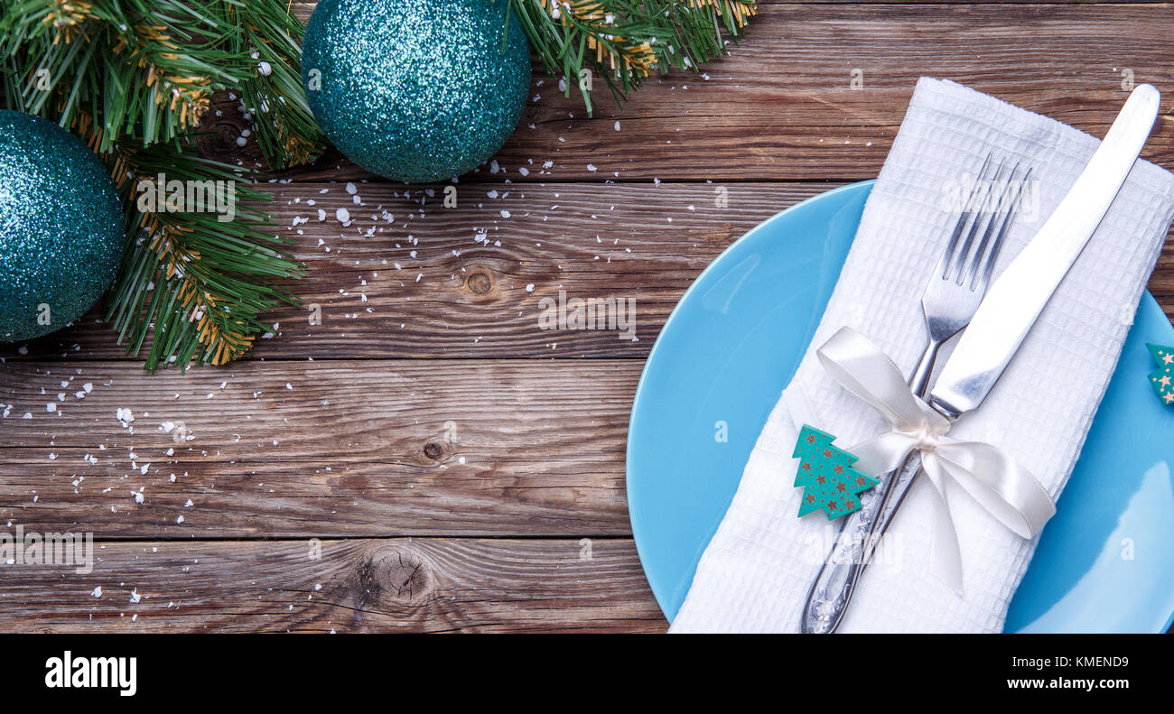 Table de noël place avec plaque bleue, fourchette et couteau, ruban et  l'arc avec décoration de sapin blanc, jouets de Noël serviette et branches  de pins avec des boules de noël Photo