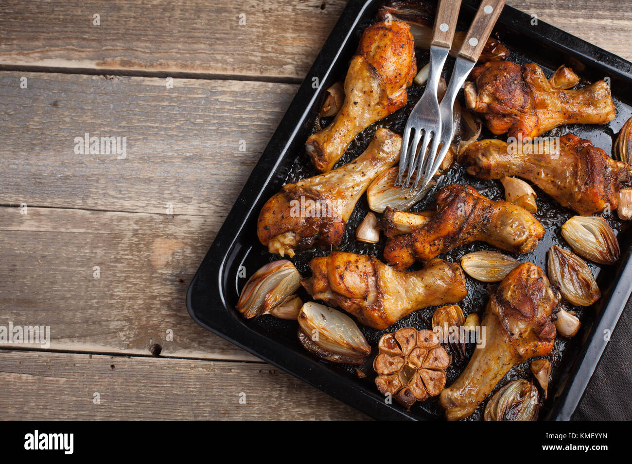 Des cuisses de poulet cuites au four avec des oignons, de l'ail et des  poivrons sur un fond en bois foncé.Vue de dessus avec espace de copie.Table  rustique en bois Photo Stock -