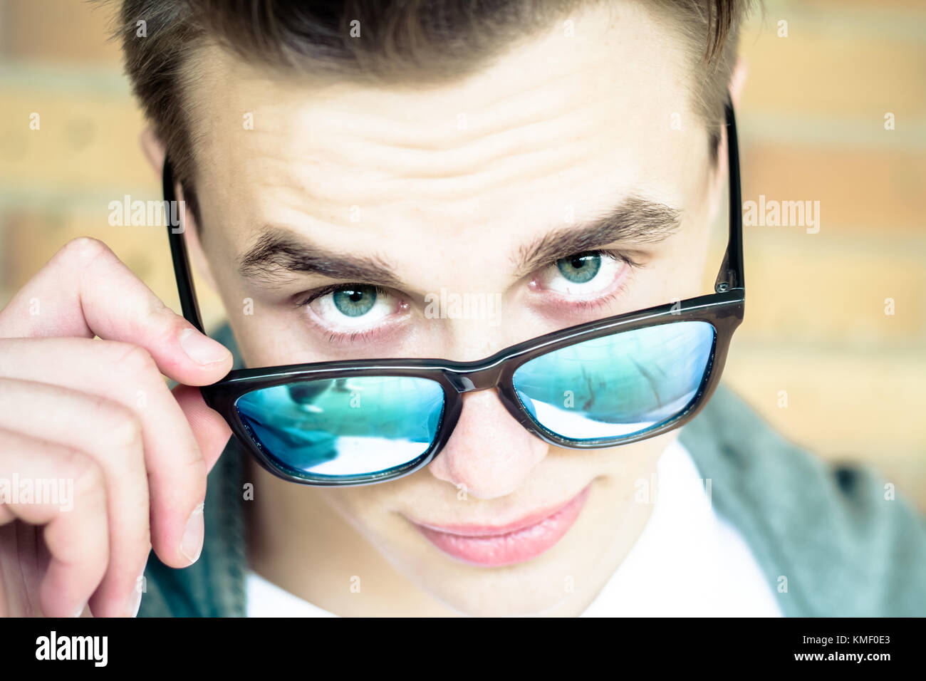 Jeune homme tenant des lunettes de soleil et à huis clos Banque D'Images