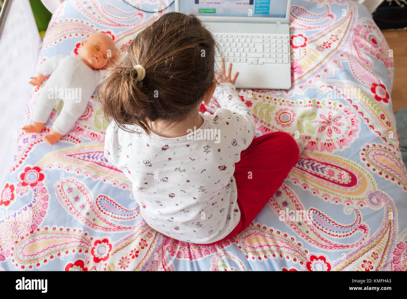 Petite fille assise dans le lit et jouer à des jeux en ligne dans sa chambre. High angle view Banque D'Images