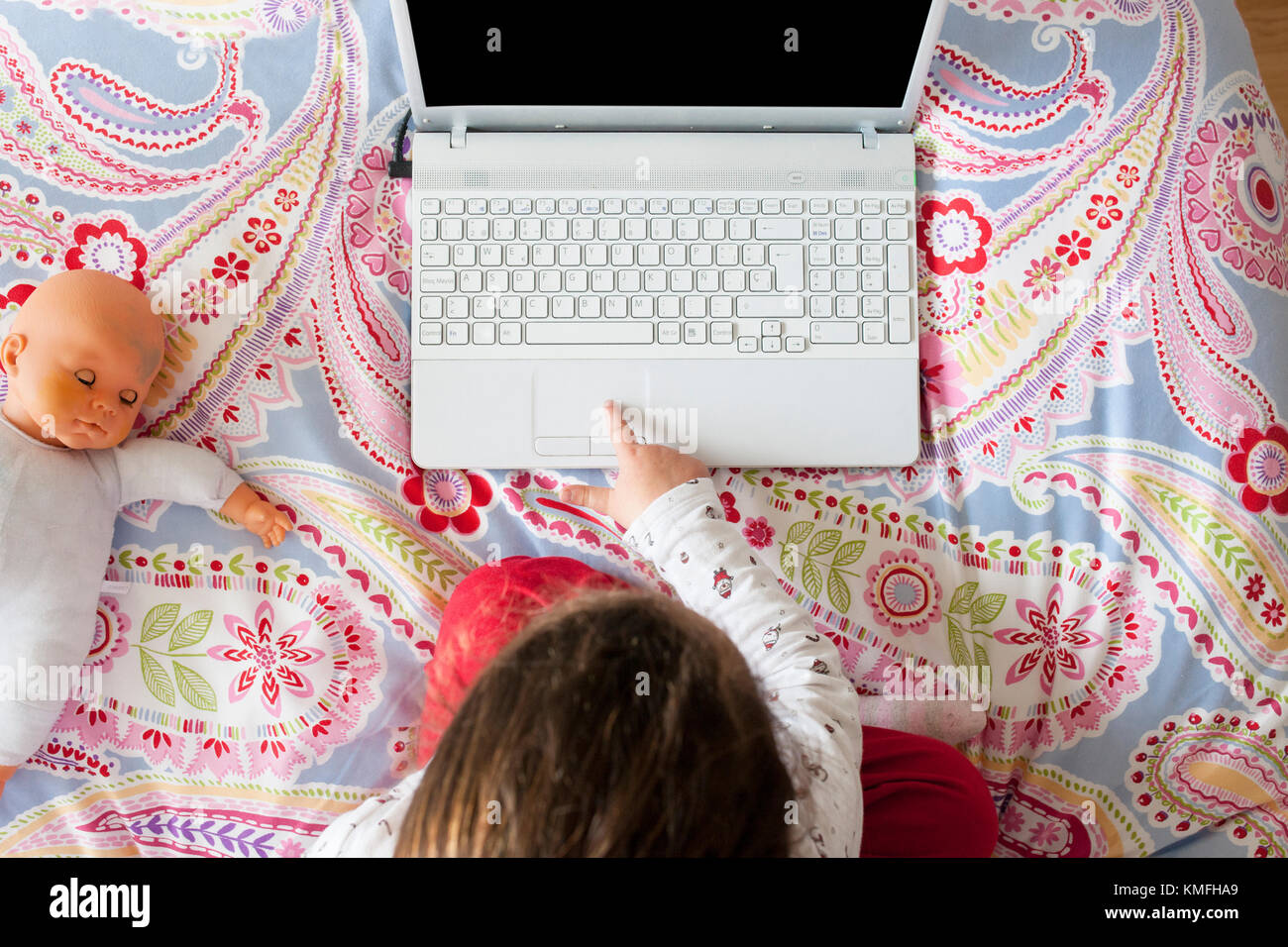 Petite fille assise dans le lit et jouer à des jeux en ligne dans sa chambre. High angle view Banque D'Images