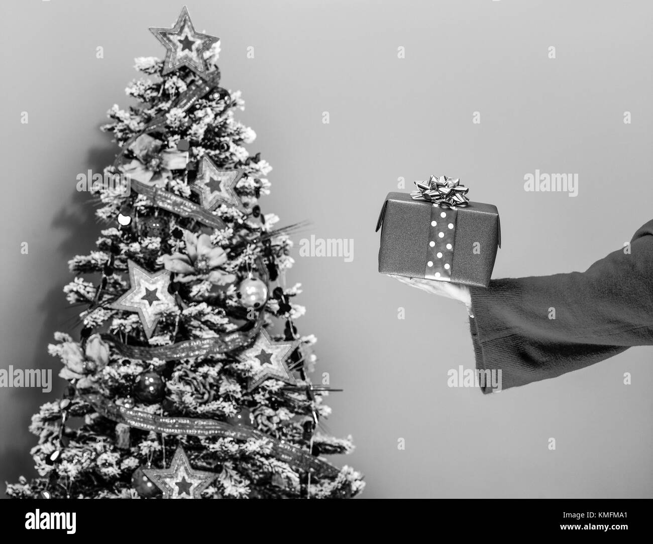 La saison de fête. Gros plan sur jeune femme dans des vêtements colorés près de l'arbre de Noël isolé sur fond jaune montrant cadeau de Noël fort Banque D'Images
