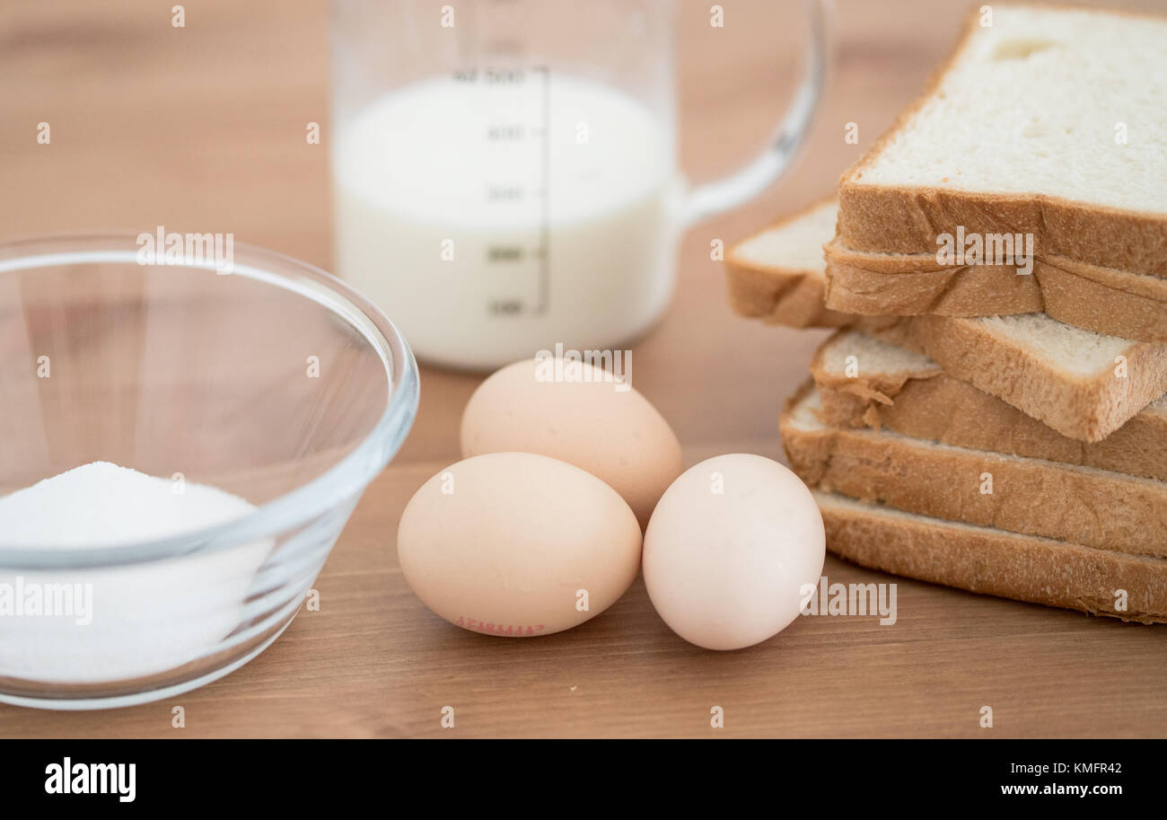 Tous les ingrédients de la recette de pain perdu - oeufs pain au lait et sucre sur fond de bois Banque D'Images