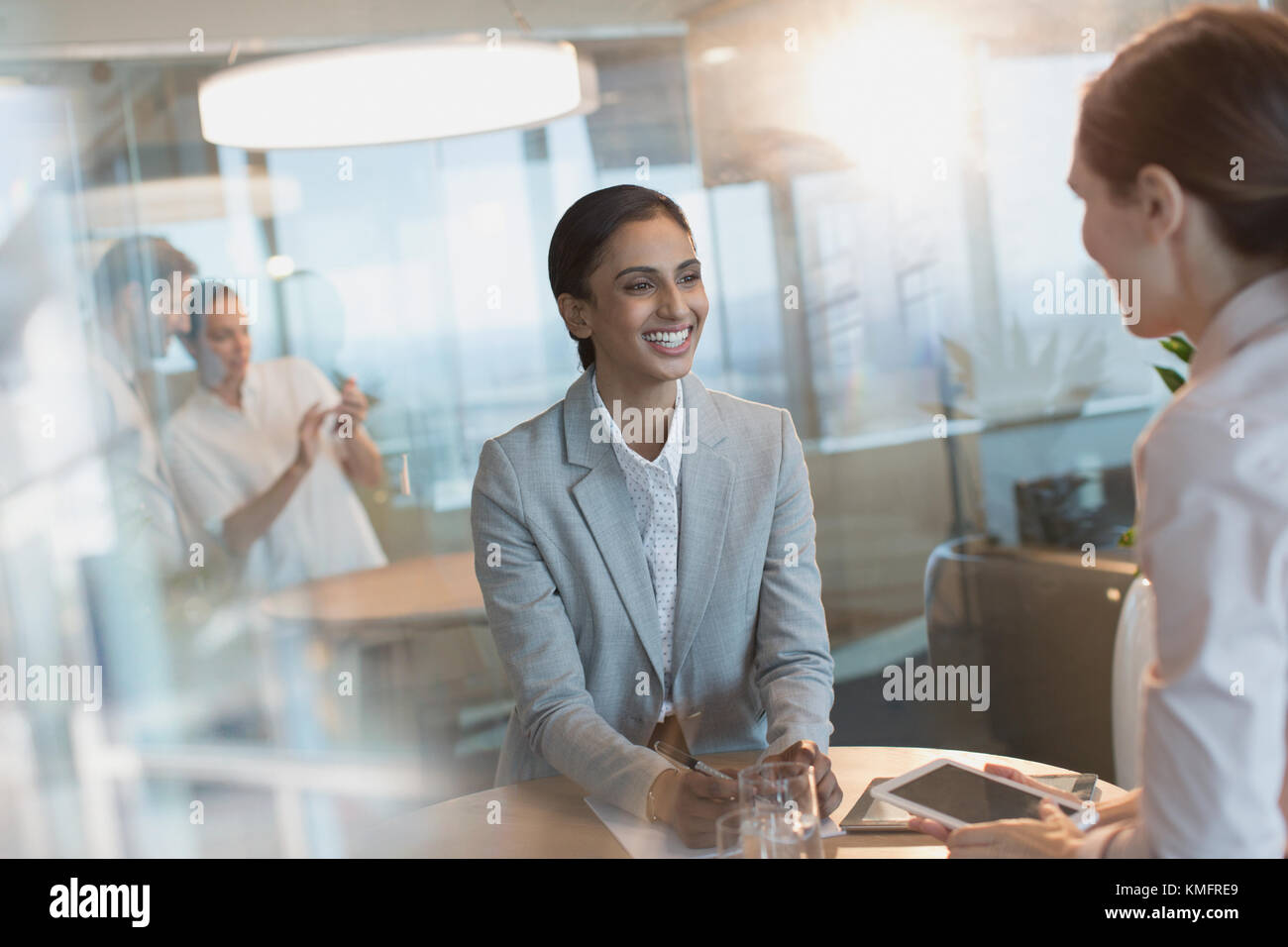 Smiling businesswomen talking, à l'aide de tablette numérique dans la salle de conférence réunion Banque D'Images