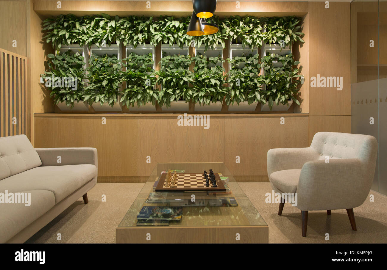 Salon avec exposition de plantes, échiquier et sièges Banque D'Images