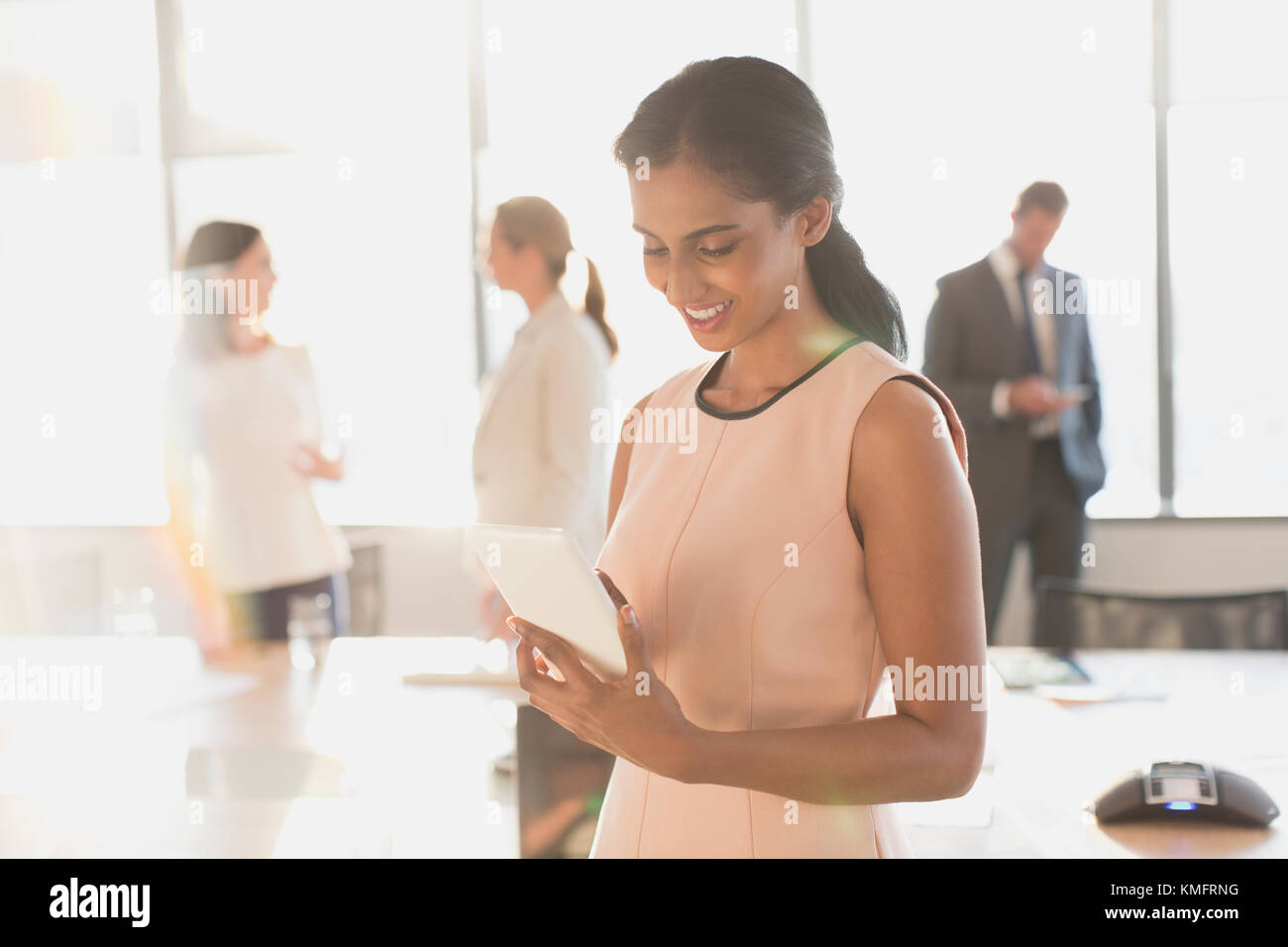 Femme d'affaires utilisant une tablette numérique dans une salle de conférence ensoleillée Banque D'Images