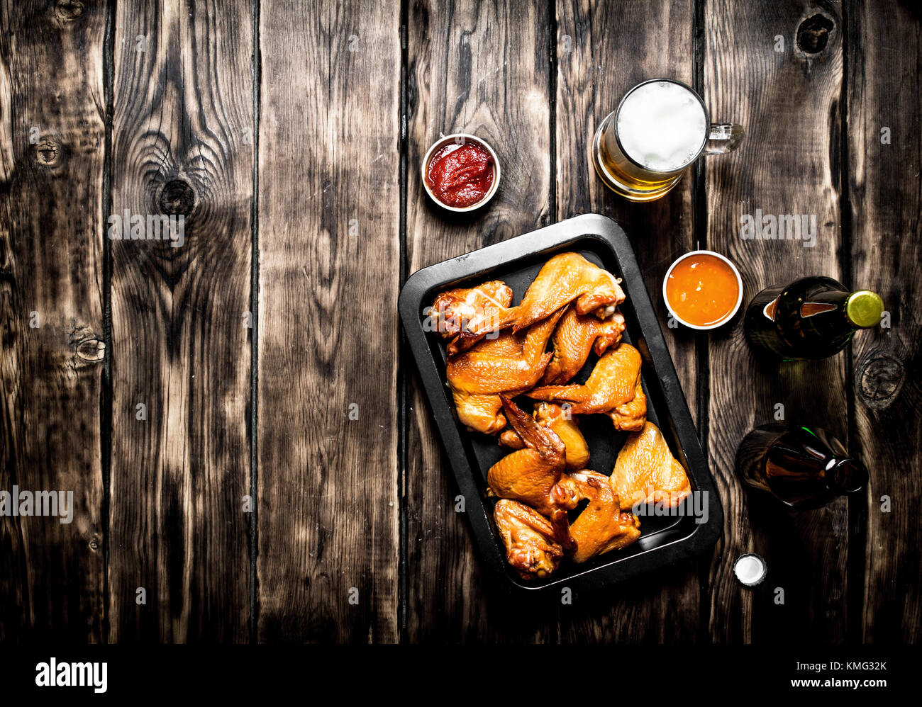 Ailes de poulet fumé à la bière et sauce. sur une table en bois. Banque D'Images