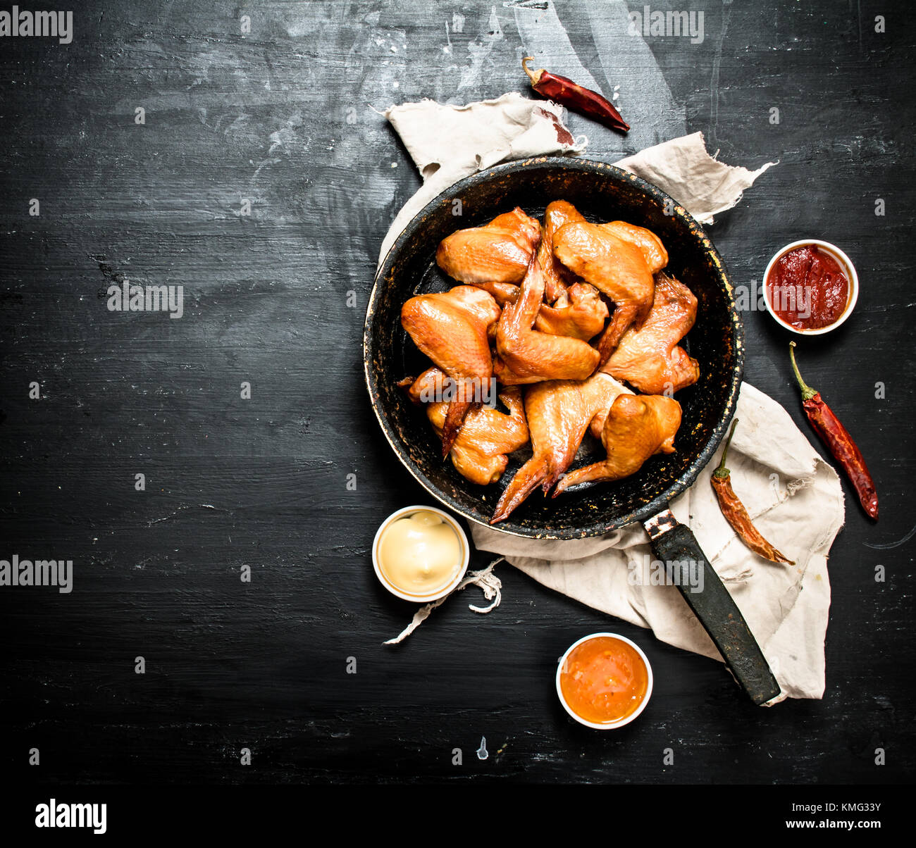Ailes de poulet fumé à la poêle avec la sauce. Le tableau noir. Banque D'Images