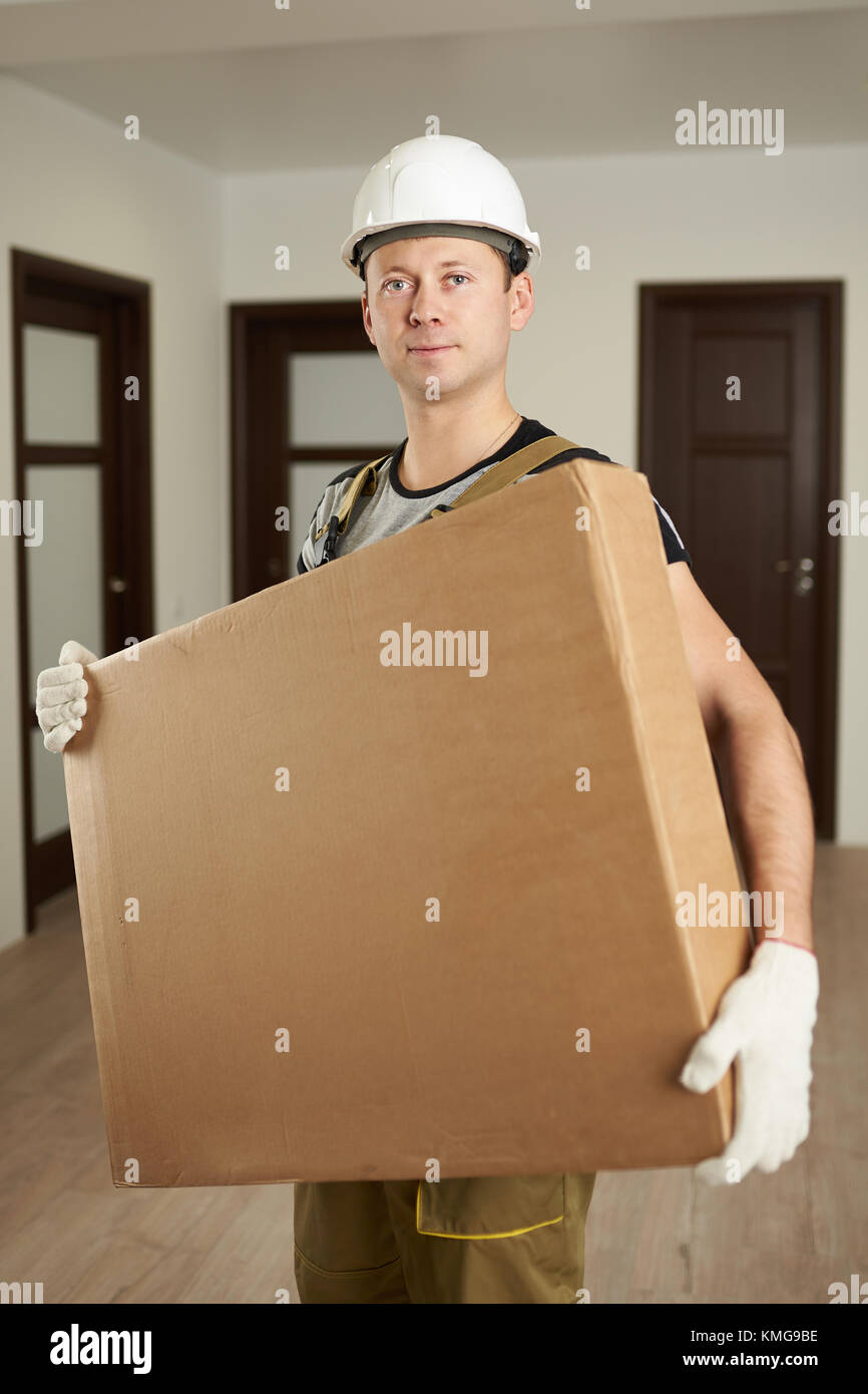 Livraison de meubles. man worker in hard hat holding cardboard box Banque D'Images