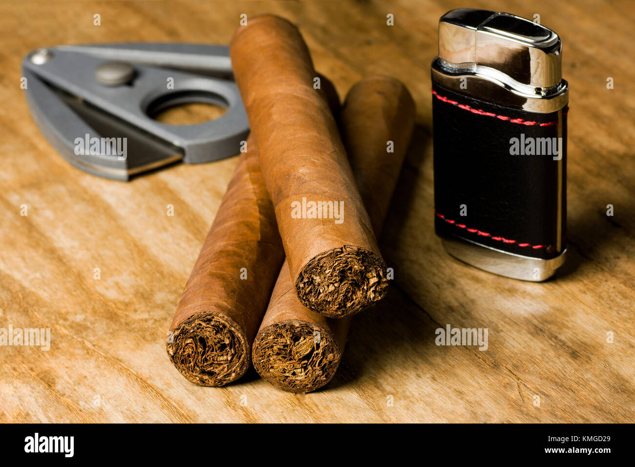 Trois cigares cubains avec un briquet et un couteau sur une vieille table en bois Banque D'Images