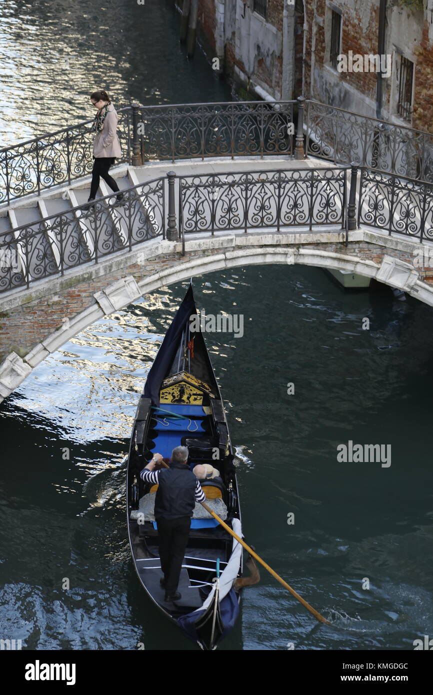 Une télécabine transporte les passagers sous un pont sur un canal étroit à Venise, Italie. Banque D'Images
