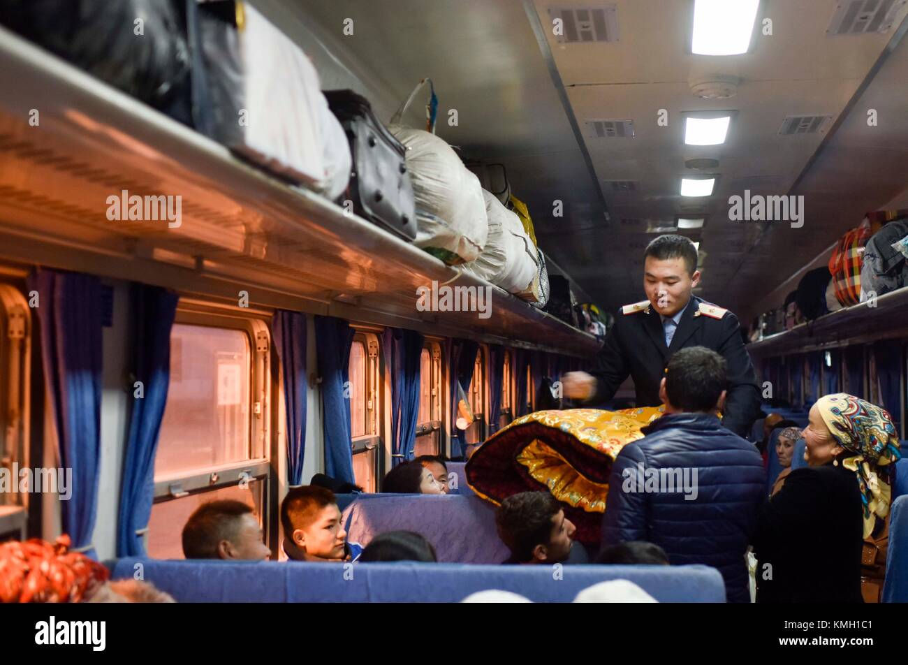 (171209) -- URUMQI, Dec. 9, 2017 (Xinhua) -- un accompagnateur aide les passagers avec des bagages sur le train n° 5809 reliant Kashgar et Hotan dans la région autonome ouïgur du Xinjiang, au nord-ouest de la Chine, 24 novembre 2017. La ligne ferroviaire de 485 km reliant deux grandes villes oasis, Kashgar et Hotan, traverse certaines des zones les plus reculées du Xinjiang et a transformé la vie dans le désert depuis son lancement en 2011. C'est le premier et le seul chemin de fer de Hotan, via le chemin de fer la préfecture sous-développée est reliée au reste du réseau ferroviaire du pays, qui compte 22 000 km de lignes ferroviaires à grande vitesse. Pauvre tra Banque D'Images