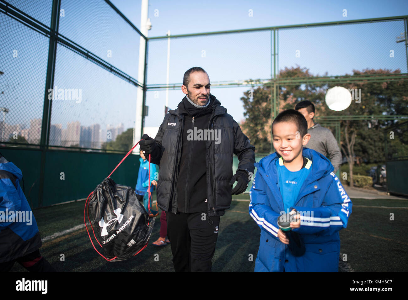 Wuhan, Chine. Déc 10, 2017. (171210) -- Wuhan, 10 décembre 2017 (Xinhua) -- Sergio Ledesma Vara (L), un entraîneur de football de l'Espagne, entre dans le terrain d'entraînement avec les élèves pour commencer la formation à Wuhan, province du Hubei en Chine centrale, le 26 novembre 2017. Sergio Ledesma Vara, 36, est venu à Wuhan en tant qu'entraîneur de football, il y a trois ans dans le cadre d'un programme appuyé par la Ville de Wuhan à introduire une dizaines d'entraîneurs étrangers à former ses jeunes prometteurs joueurs de football. Sergio est très occupé chaque semaine. Chaque matin, il fait un plan de formation avec des entraîneurs chinois et dans l'après-midi des trains sur 20 joueurs tout à l'ag Banque D'Images