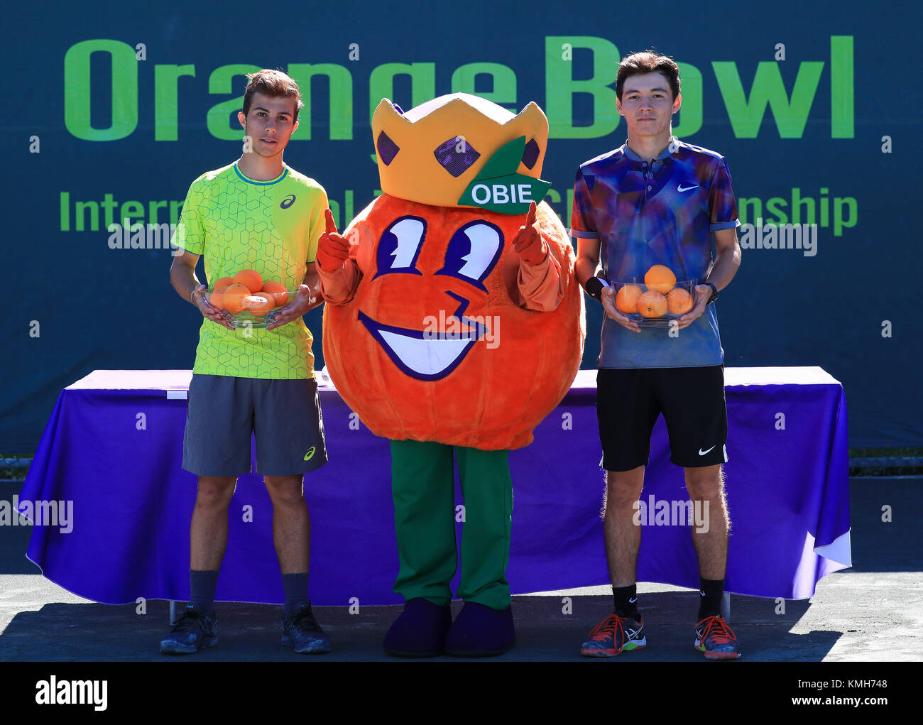 Plantation, Florida, USA. Déc 10, 2017. Hugo GASTON (FRA), gauche, gagnant de la finale des garçons de 18 ans de l'Orange Bowl 2017 Championnat International de Tennis, et Dostanbek TASHBULATOV (KAZ), droite, finaliste, poser, Obie, le centre de Bol Orange officiel mascot, comme ils tiennent leurs trophées lors de la cérémonie du championnat, à la Frank Veltri Tennis Center à Plantation, en Floride, aux États-Unis. Tashbulatov Gaston a battu 6-2, 6-3. Mario Houben/CSM/Alamy Live News Banque D'Images