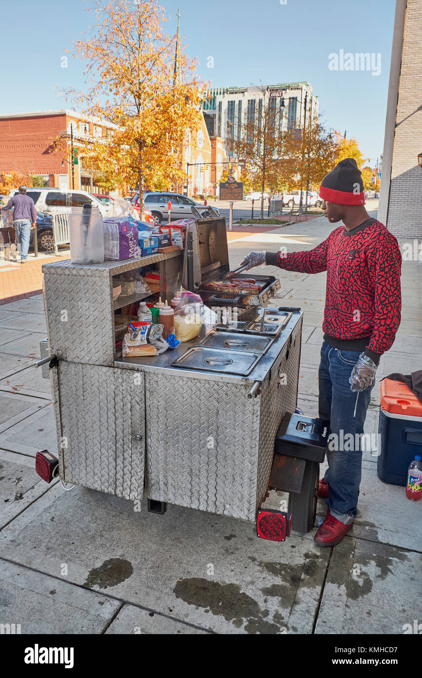 Mâle noir, afro-américain, vendant des hot-dogs depuis son chariot sur le trottoir de la ville. Banque D'Images