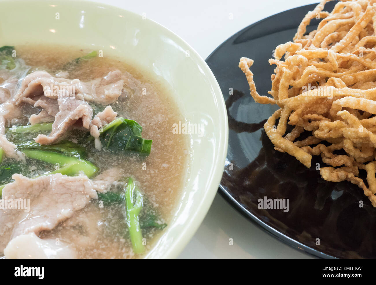 Sauce sauce crémeuse avec du porc et croustillant nouilles jaune sur le tableau blanc dans un restaurant thaïlandais. Banque D'Images
