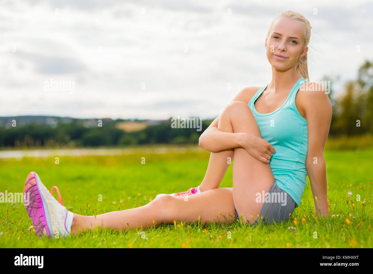 Femme blonde fit s'étendant sur l'herbe en plein air Banque D'Images