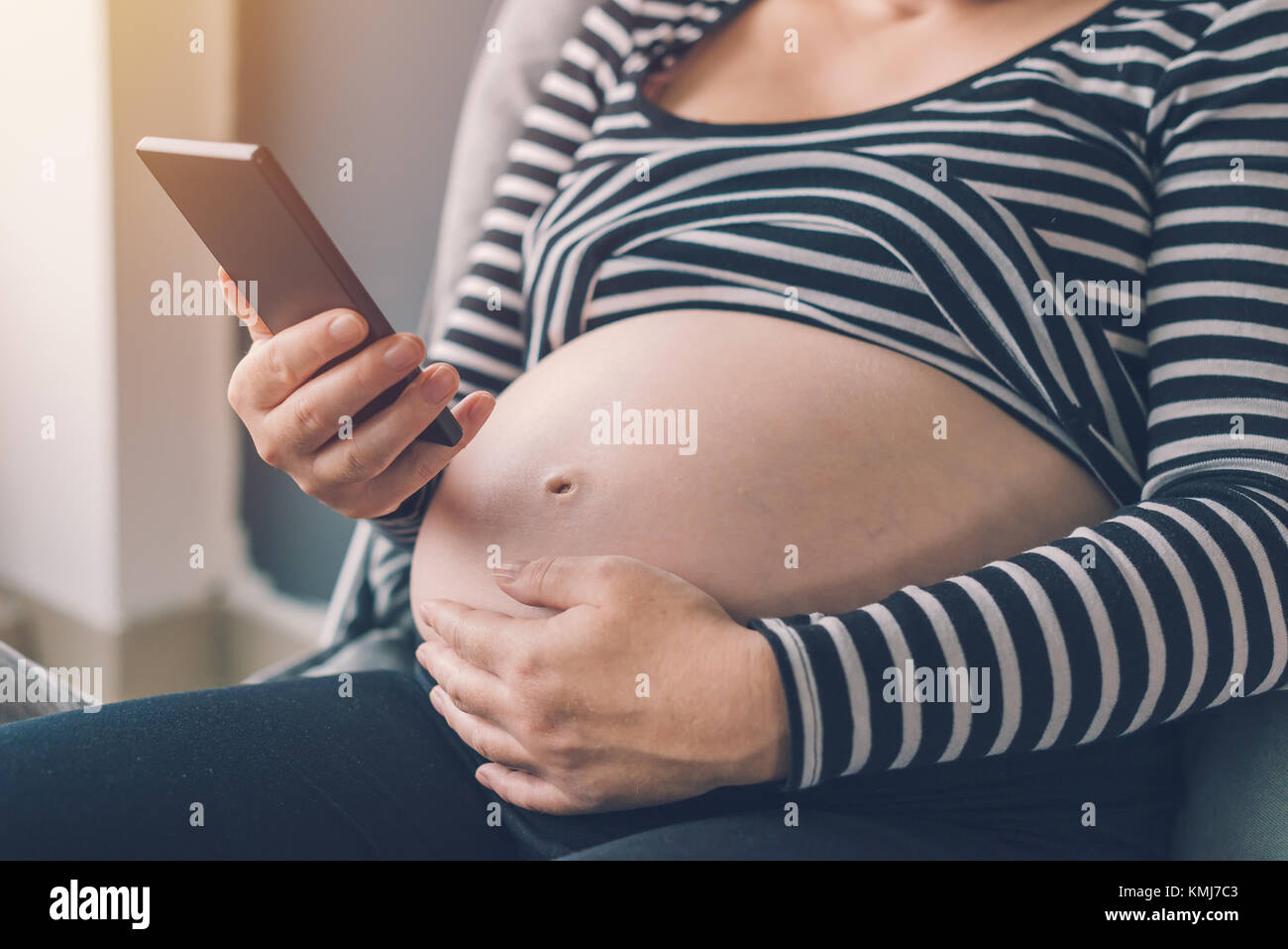 Femme enceinte en utilisant son smartphone pendant la grossesse Banque D'Images