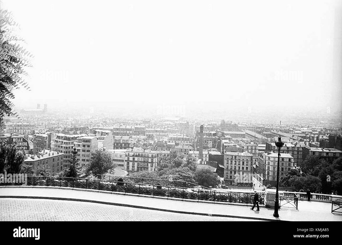 Cette photographie en noir et blanc capture une vue de Paris depuis Montmartre en 1934. La photo met en valeur l'emblématique horizon parisien, avec des monuments tels que la Tour Eiffel visibles en arrière-plan. L'image reflète le paysage historique et culturel du cityÂ€™ au début du XXe siècle. Banque D'Images