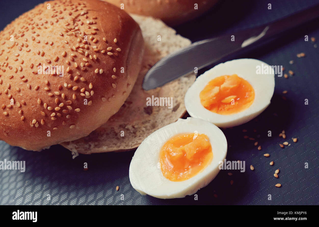 Vue de dessus de petits pains frais avec fromage doux et œufs durs sur une planche à découper. graines de sésame. petit déjeuner rapide concept , focus sélectif, tonique, Close up Banque D'Images