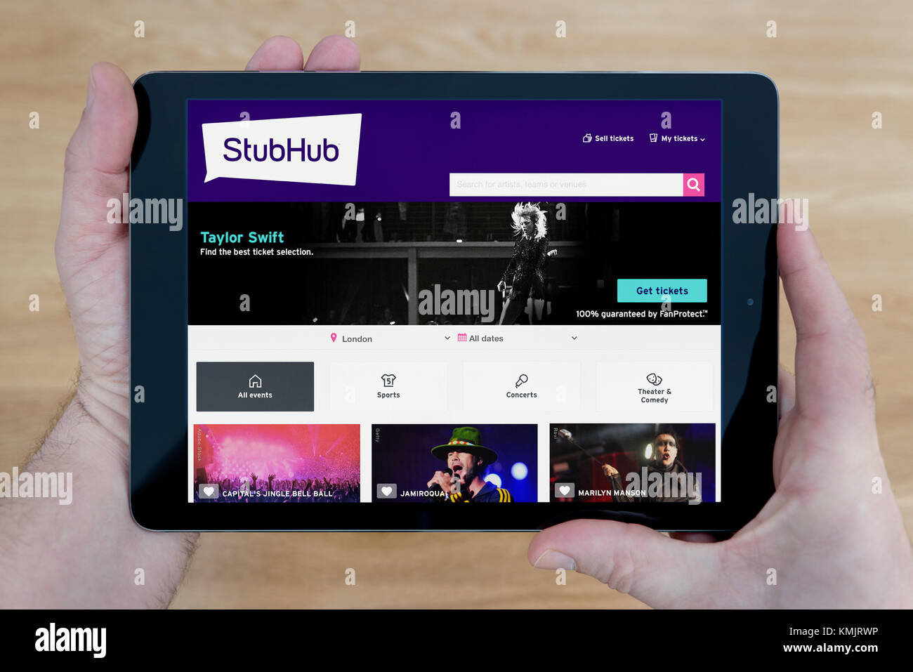 Un homme regarde le site StubHub sur son iPad tablet device, tourné contre une table en bois page contexte (usage éditorial uniquement) Banque D'Images