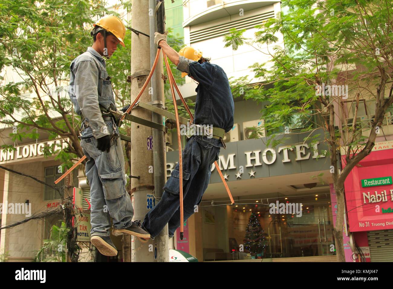 Poseur travaillant sur des lignes de transport d'électricité à Saigon, Vietnam Banque D'Images