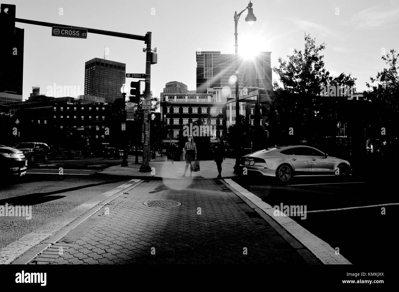 Femme éclairée par la lumière du soleil reflétée en tant qu'elle attend pour traverser à un passage à niveau de la rue piétonne à Boston, Mass., USA Banque D'Images