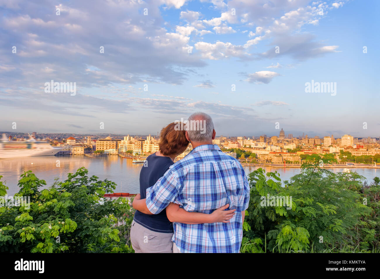 Un homme aux cheveux gris et une femme aux cheveux rouges se tiennent, embrassant et admirant la ville antique et le paquebot blanc sur l'océan au quai du port Banque D'Images
