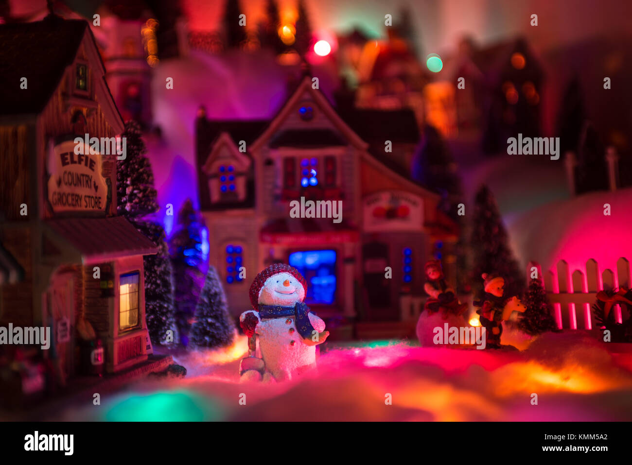 Au-dessus de feux brille sur happy face de bonhomme qui se dresse au milieu d'une place de marché miniature en hiver noël avec les enfants Banque D'Images