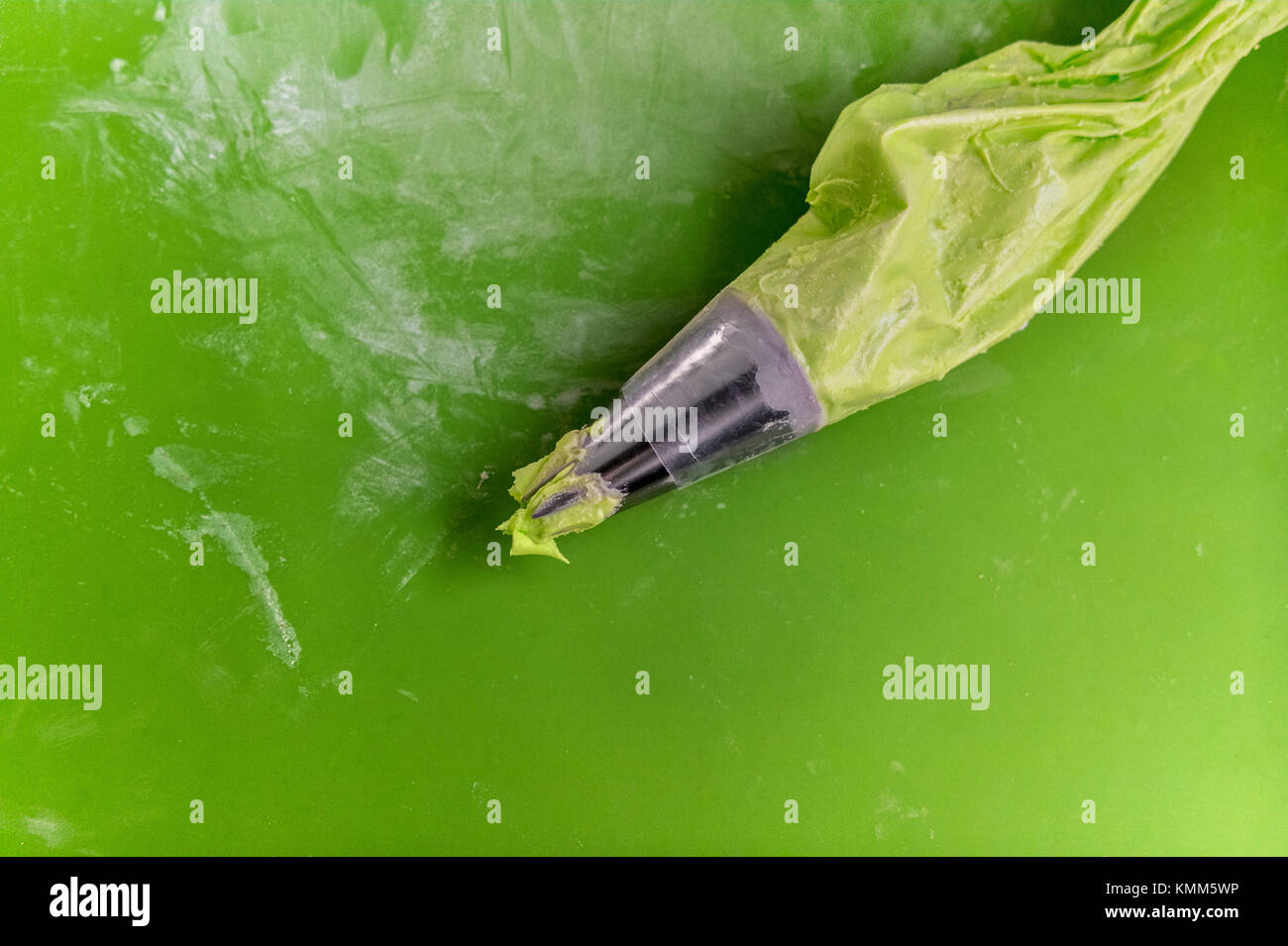 Glaçage vert Sac de pâtisserie sur un tapis vert. Banque D'Images