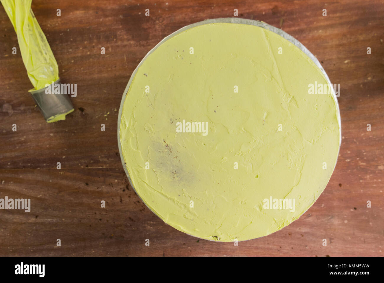 Gâteau rond jaune et poche à pâtisserie sur fond de bois. Banque D'Images