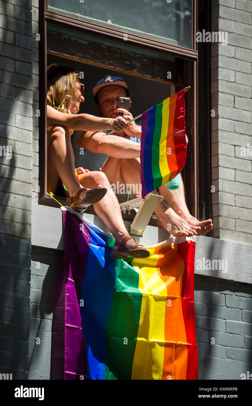 New York - 25 juin 2017 : vague de drapeaux arc-en-ciel partisans un appartement d''une fenêtre donnant sur la gay pride parade annuelle à Greenwich village. Banque D'Images