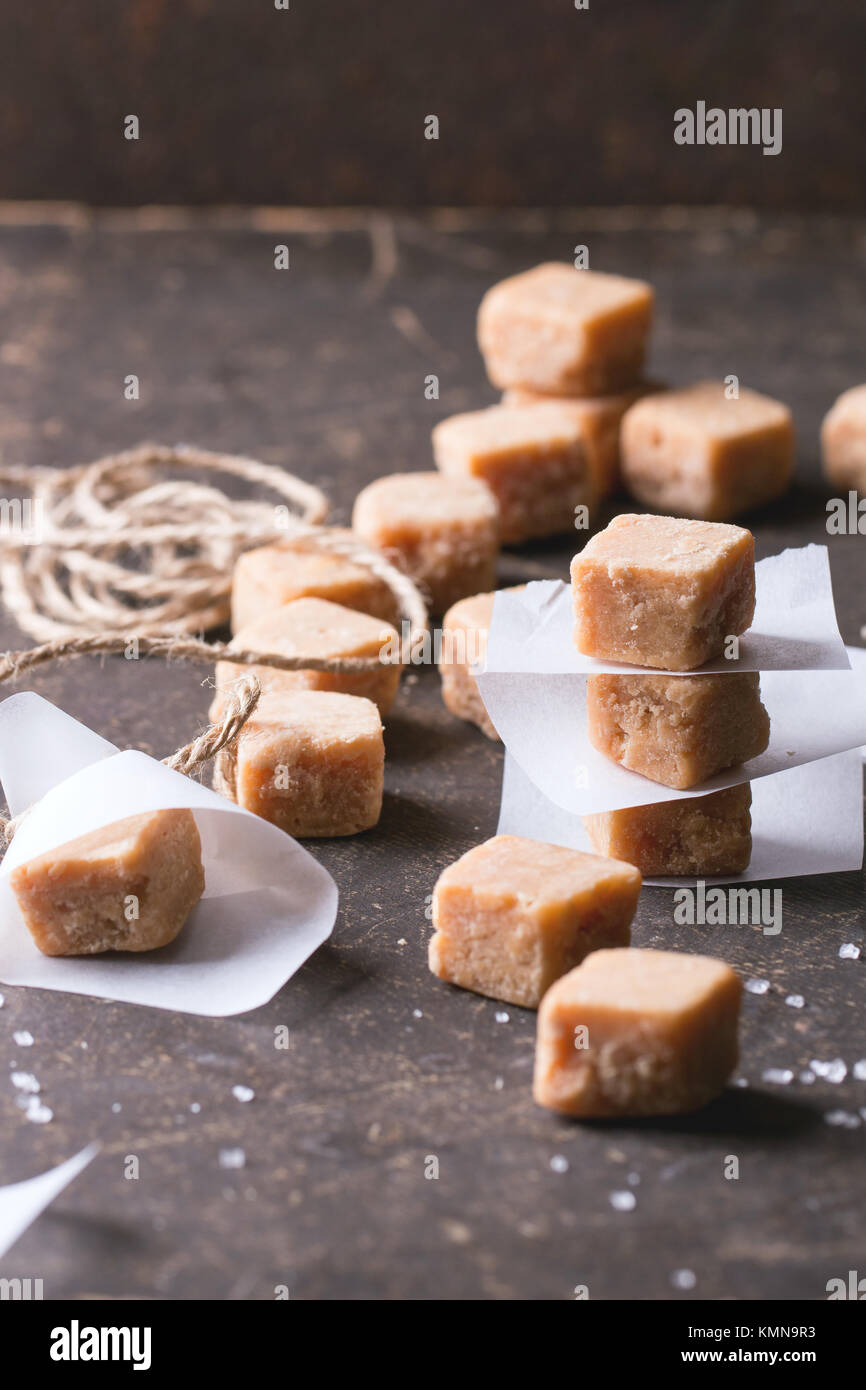 Bonbons au caramel Fudge et sur du papier sulfurisé, servie sur fond sombre. Banque D'Images