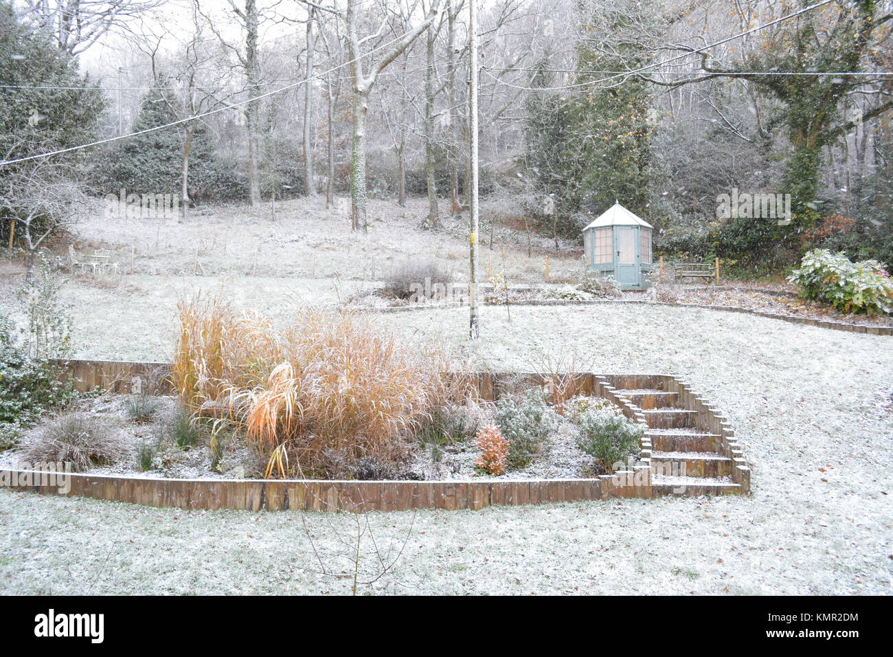 Grand jardin en pente avec maison d'été en hiver avec la neige légère couvrant d'arbustes arbres arbustes et simples dans l'herefordshire angleterre UK Banque D'Images