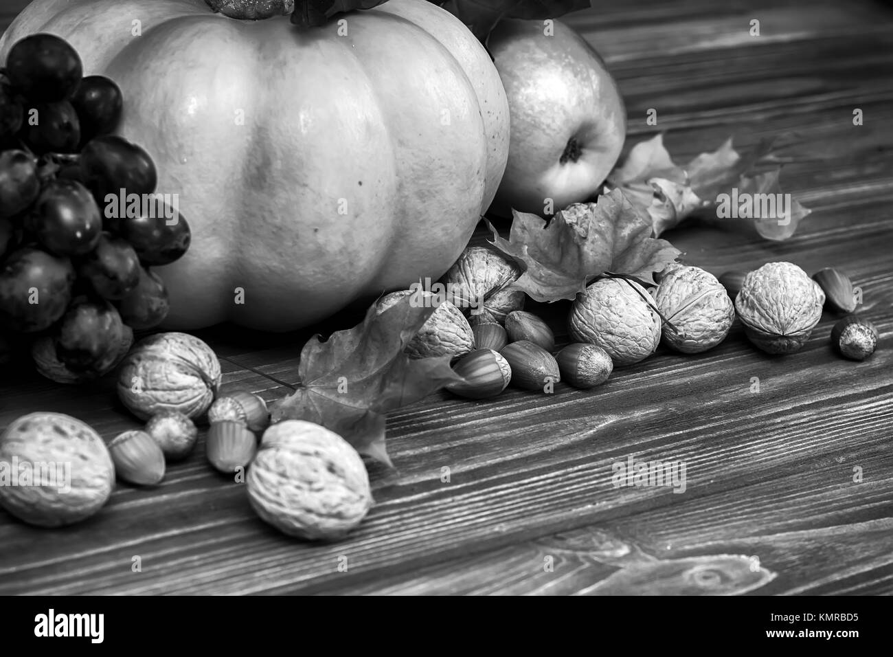 Citrouille, pomme, noix, baies avec feuilles d'érable sur fond de bois. Carte d'automne de grâce. L'Halloween. Dans les tons noir et blanc Vintage Banque D'Images