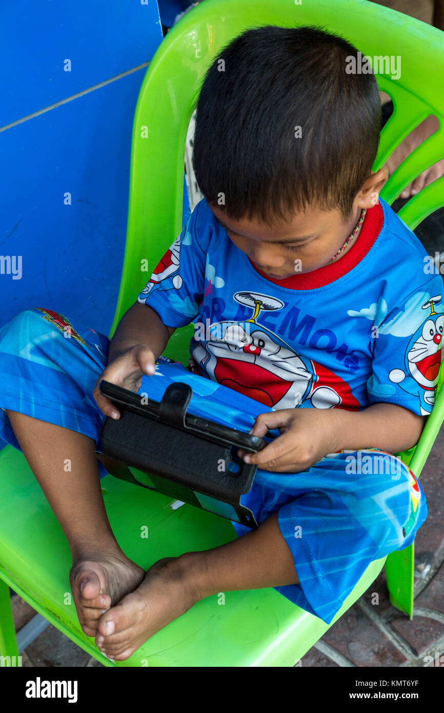 Bangkok, Thaïlande. Petit Garçon jouant jeu vidéo sur téléphone cellulaire. Banque D'Images