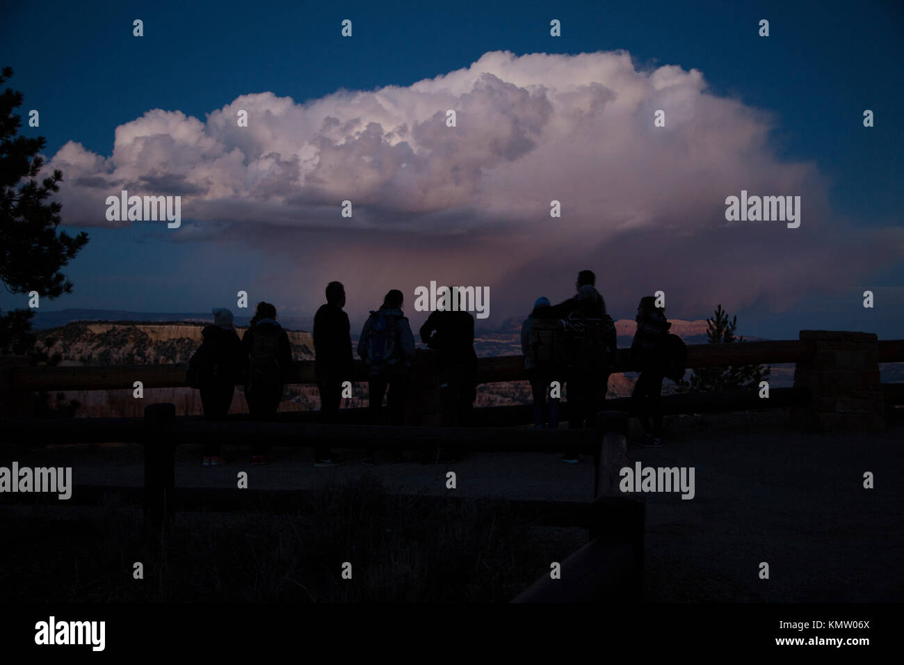 Un groupe de touristes regarder un orage lointain au crépuscule à un belvédère à Bryce National Park dans l'Utah. Banque D'Images