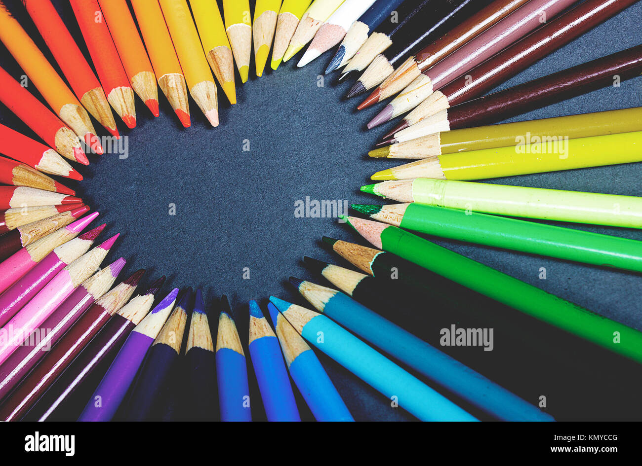 Crayon de couleur en couleur arc-en-ciel résumé fond fixant dans la forme f un coeur sur fond gris Banque D'Images