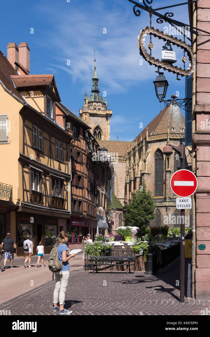 Un touriste consulte un plan de la rue de l'Église avec les traditionnelles Maisons à Colombages (maisons à colombages) et l'église Saint Martin de Colmar, Alsace Banque D'Images